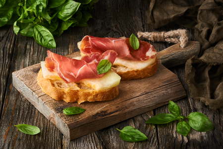 photo of tasty bread slices with bacon and melonの写真素材