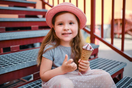 funny and happy little girl in hat eating ice cream