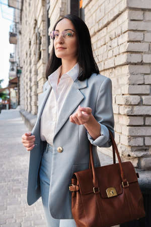 stylish businesswoman standing with bag on the city street
