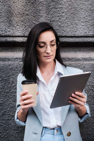 serious businesswoman holding tablet and cofeein a urban background