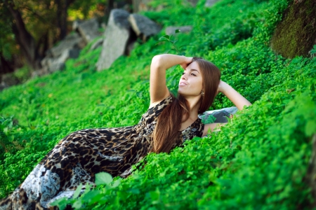 Smiling young girl lying on green grass close up,in park の写真素材