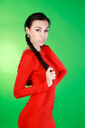 Young brunette in red dress, studio on green backgroundの写真素材