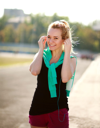 Young sporty woman in the morning with headphones on treadmill outdoorsの写真素材