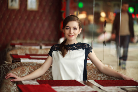 Beautiful young woman alone waiting at a table in a restaurantの写真素材
