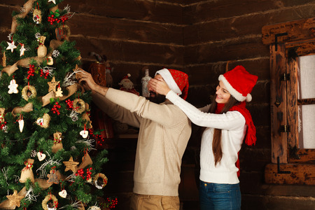 Cheerful couple decorates a Christmas tree in a country houseの写真素材
