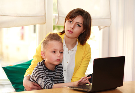 Mother and son at home doing lessons looking at laptopの写真素材