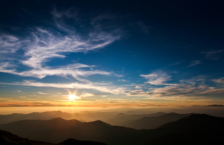 Magnificent sunset sky over silhouettes of the mountainsの写真素材