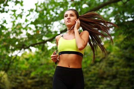 Young woman running in green park, fitness outdoors