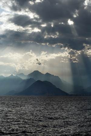 Spectacular scenery of the sea and the mountains on background of sky in the sun raysの写真素材