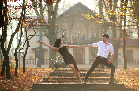 Young elegant couple man and woman passionately dancing tango in the city park at sunsetの写真素材