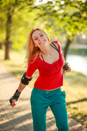 Joyful young girl in the summer city park roller skating, fun, leisure and healthy lifestyleの写真素材