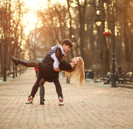 Elegant young couple in love in a classic style passionately dancing in the city park at sunsetの写真素材