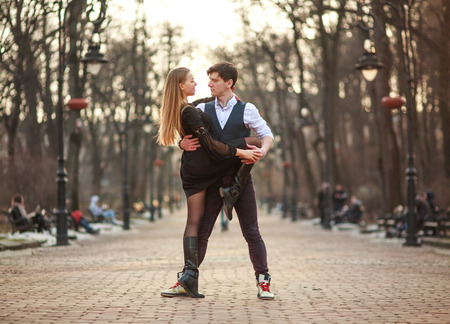 Elegant young couple in love in a classic style passionately dancing in the city park at sunsetの写真素材