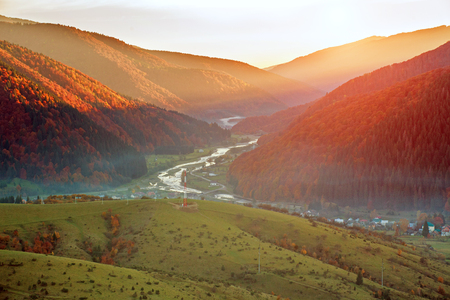 Road hiking trail in the autumn colorful mountains on background of the valley and the magnificent sunset skyの写真素材