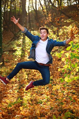 Young funny and curious handsome man jumping in a forest park, lifestyle and freedom conceptの写真素材