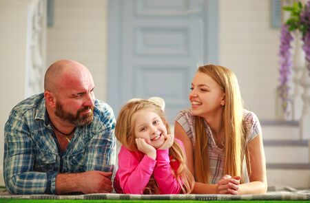 Happy young family in the yard of a house in spring garden, leisure children and parents togetherの写真素材