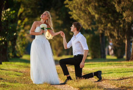 Young couple gets married in a green summer park, the guy makes a love proposal to the girlの写真素材