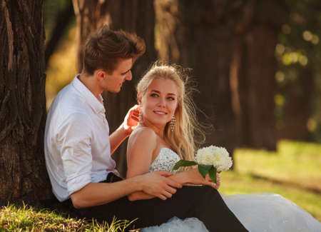 Young happy newlywed couple having fun together during the day in a summer green parkの写真素材