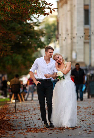 Romantic loving and happy newlywed couple walking together merrily along the street of an old European townの写真素材