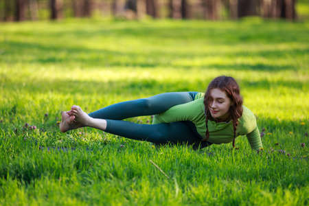 Athletic sportive girl in the park on green grass doing fitness exercises stretching the body, healthy lifestyle in pure natureの写真素材