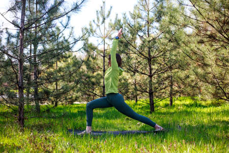 Girl doing yoga in a fir park, fitness exercise outdoors, healthy lifestyle and the freshness of pure natureの写真素材