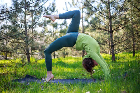 Girl doing yoga in a fir park, fitness exercise outdoors, healthy lifestyle and the freshness of...