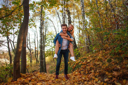 Happy young couple guy and girl enjoying nature of autumn park together