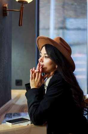 Young asian lady, in a classic business suit and hat with a newspaper in a cafe, retro character styleの写真素材