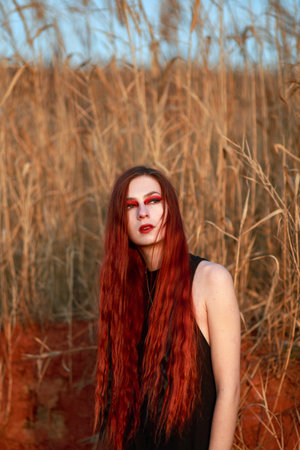 Mystical portrait of a stylish red-haired girl in black on the background of an extraterrestrial...
