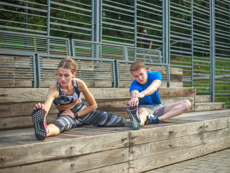 Smiling and joyful couple doing fitness exercises, in the city parkの写真素材