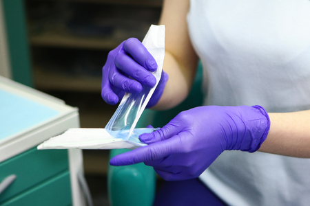 Macro photo of doctor's hands in gloves, which reveals a sterile mirror for dental work. The concept of beauty and health.Photov doctor's officeの写真素材