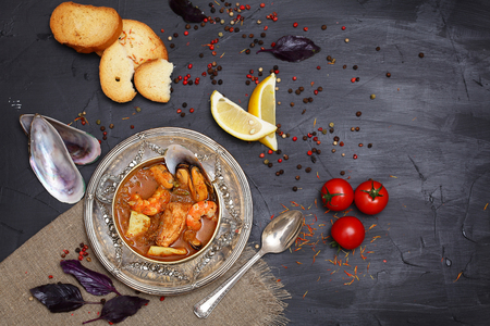 French seafood soup. Bouillabaisse ear of seafood. Vintage silver plated plate and spoon. Black background, top view. Free space for inscriptions.の写真素材