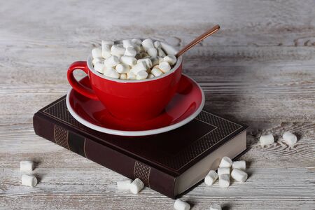 A big red cup with coffee is standing on the book. Photo on a white wooden background. View from above. Still life concept.の写真素材