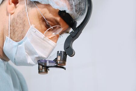 Close-up of a dentist surgeons face with a microscope in glasses. Binocular glasses. Copy space.の写真素材