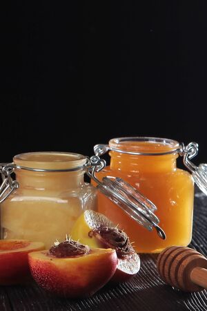 Apricots in half and jars of honey on a black background. Out of focus. Still life concept. Copy space. Macro photo.の写真素材