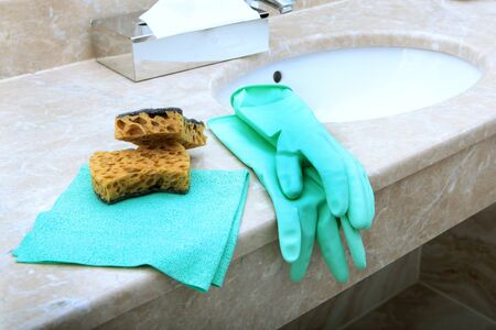 Green rubber or latex gloves and a cleaning sponge lie on the marble sink in the bathroom. The view from the top. Items of sanitary hygiene and disinfection. Copy space.の写真素材