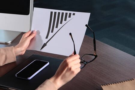 A business woman holds in her hands a graph of the economic crisis or decline in production....
