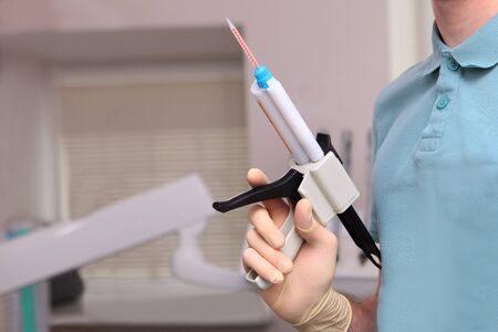 Dental gun for casts in the hands of the doctor. Unrecognizable photo. Copy space.の写真素材