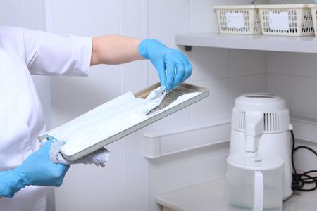 An employee of the dental clinic lays out sterile sets of tools. The concept of sterility and...