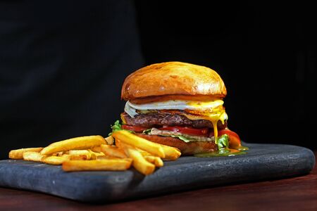 A large hamburger and French fries on a black background. Horizontal photo. Photos without people. Copy spaceの写真素材