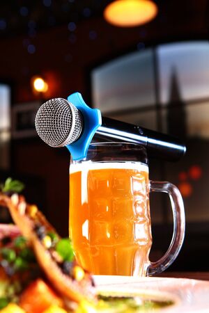 The karaoke microphone is on top of a beer mug.A plate of food on the table. The concept of a karaoke restaurant. Copy space.の写真素材