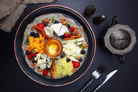 Cheese plate with honey on a dark background. Selection of cheeses. Appetizer with wine. Copy space. Top view.の写真素材