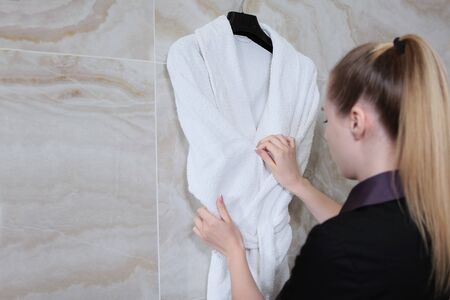 The cleaner adjusts her robe in the bathroom. Cleaning service at the hotel or at home.Unrecognizable photo. Copy space.の写真素材