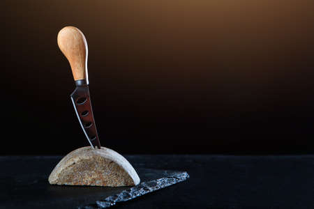 Cheese knife. A piece of homemade craft cheese. Organic food. Copy space. Photo on a black background.の写真素材