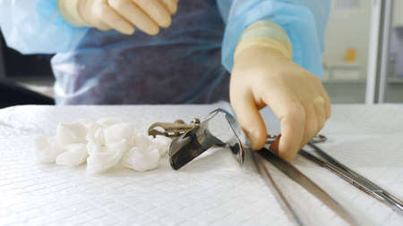 Close-up of the hands of a gynecologist in gloves. The doctor takes a speculum and other medical...