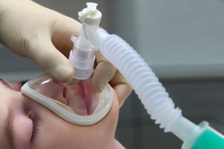 Administration of anesthesia before surgery to a young boy. Breathing mask on the childs face. Copy of the space.の写真素材