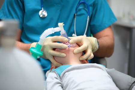 Preparing a young boy for dental surgery. General anesthesia. Treatment of multiple caries of baby teeth. The device of artificial ventilation of lungs. Copy of the space.の写真素材