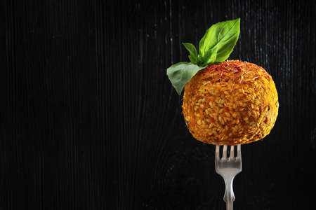 Soft dessert cheese with sesame and spices on a fork. Photo on a black background. Mint leaves on top. Copy of the space.の写真素材