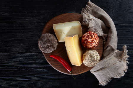 Assorted hard cheeses and cheeses with black and red hot peppers. The concept of still life.Copy of...