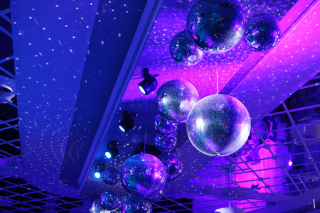 Disco ball with bright rays, night party with blue background. Party dance hall celebration at night club with lots of flashy colors. Rotating disco mirror ball.の写真素材